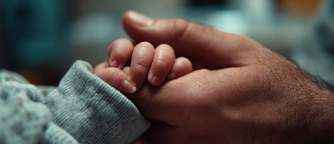 Mão de adulto segurando a mão de um bebê